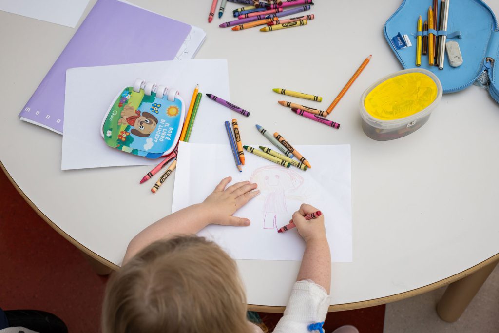 Foto di un bambino ricoverato in ospedale che fa un disegno con i pastelli colorati